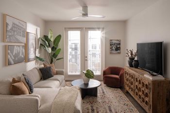 A living room with a couch, a chair, a coffee table, and a television
